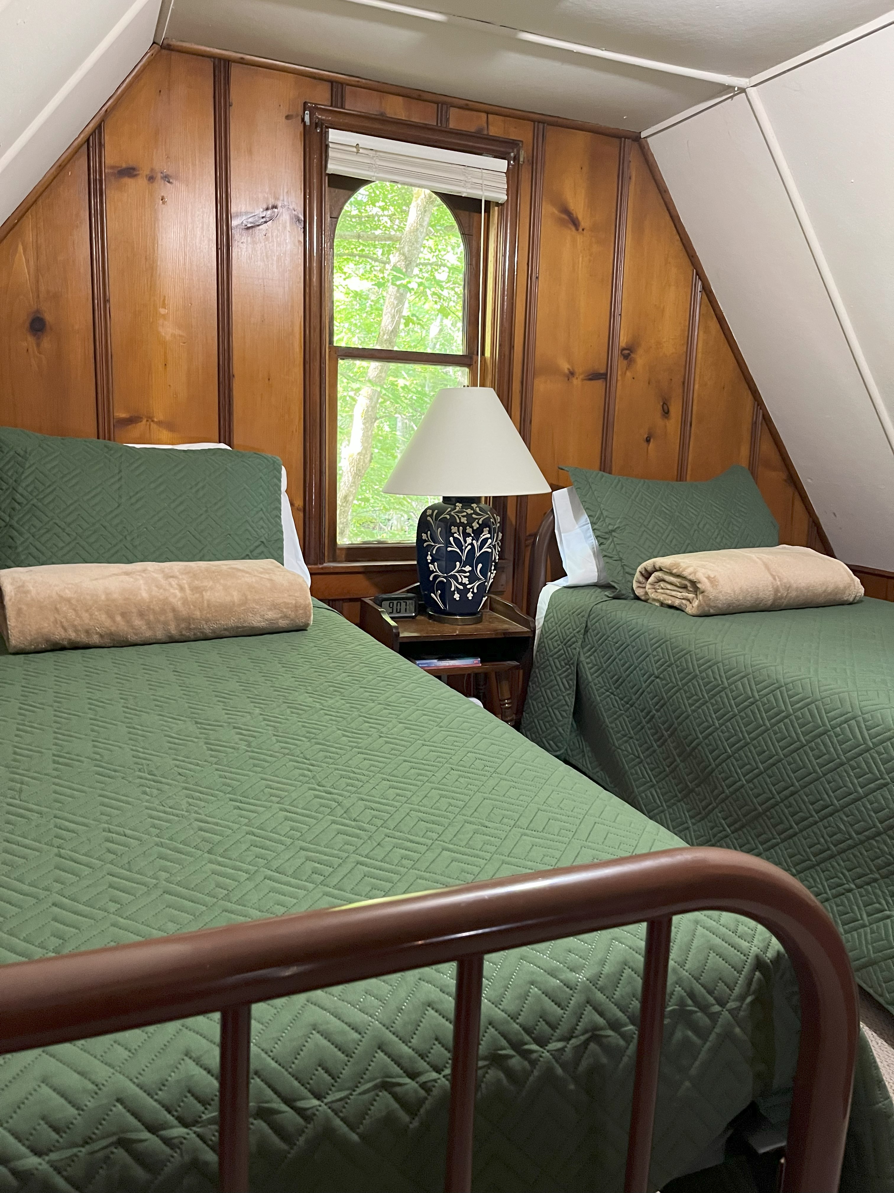 Sleeping loft with twin beds and green quilts